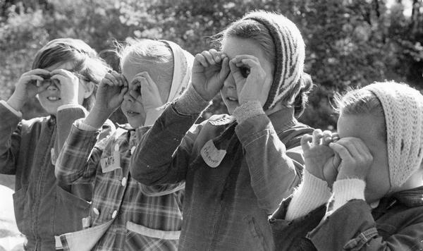 Girls wearing head scarves form their fingers to make "binoculars" on a sunny autumn day.
