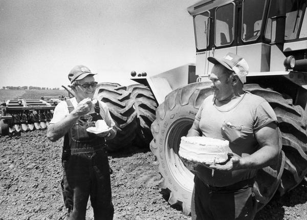 John Fitzsimmons and Barton Voegeli take a break from discing the fields to eat the birthday cake that Voegeli's wife made to celebrate the occasion.