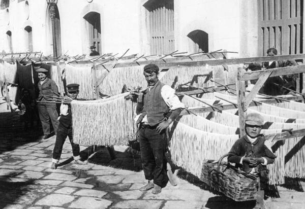 Workers posing with racks of fresh pasta drying in the sun in Naples, Italy.
