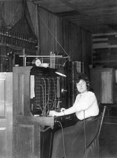A female telephone operator posing sitting at the switchboard.