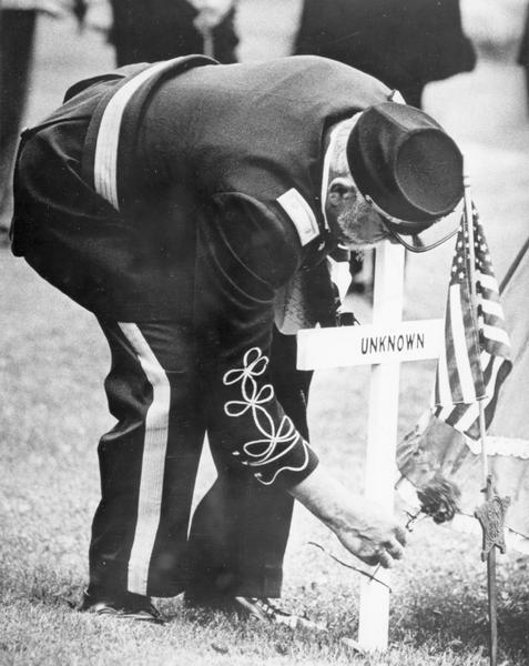 A veteran places a flower on the grave of an unknown soldier.