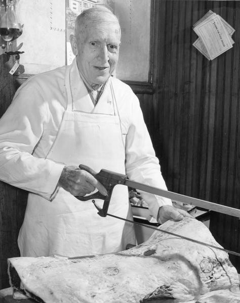 Butcher Herman Nimmer positions his hand saw to cut a slab of meat.