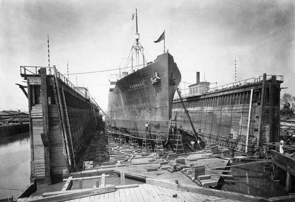 The ship, "Cushnoc" is surrounded by scaffolding as men conduct maintenance on her hull.