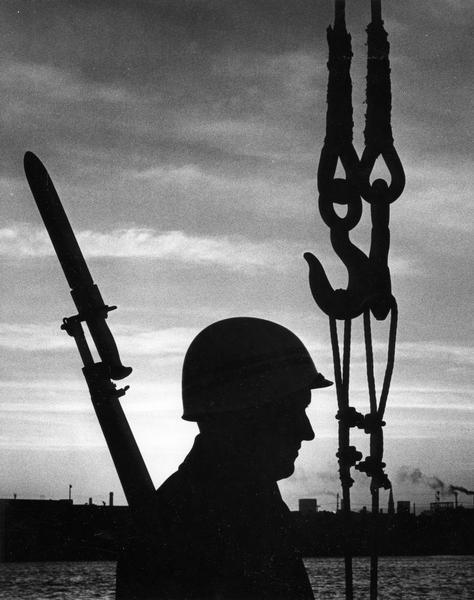 Silhouette of a guard patrolling while wearing a helmet and carrying a bayonet.