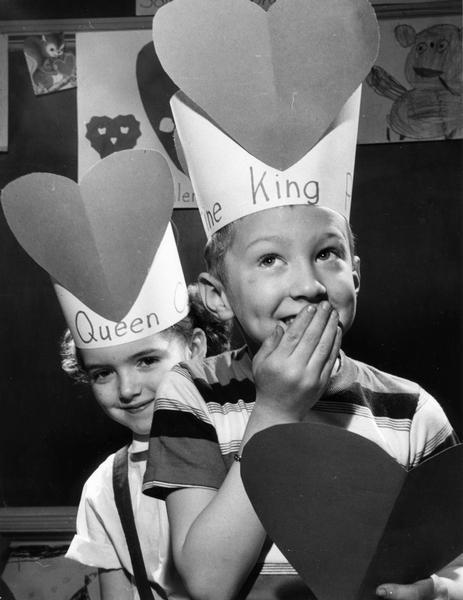 Crowned queen and king of Valentine's Day celebrate over a card.