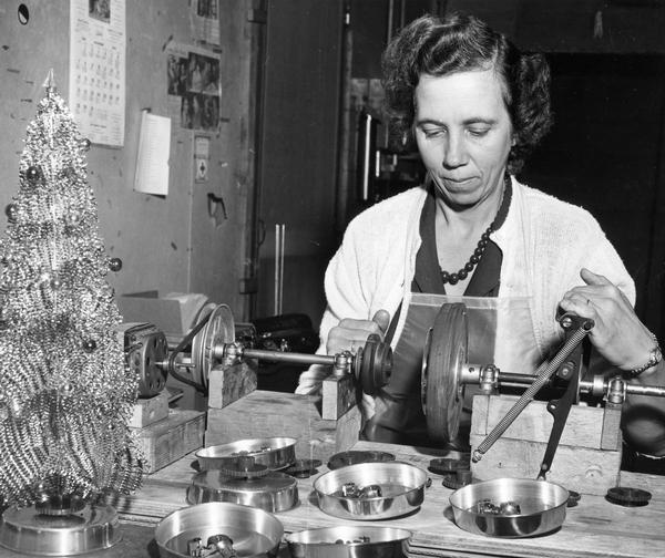 A woman looks over parts used as bases for miniature Christmas trees.