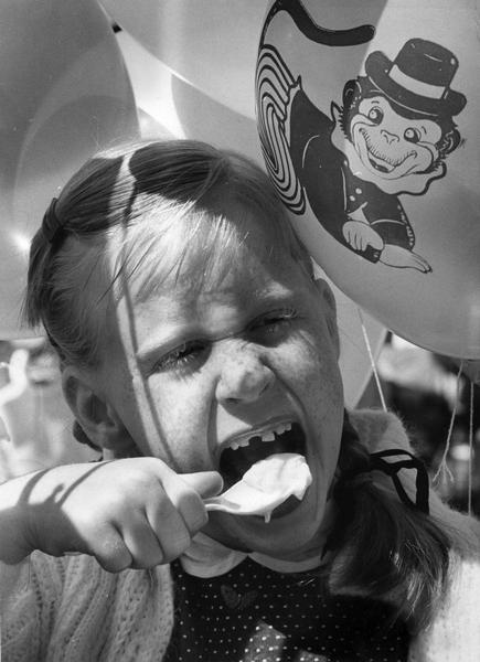 Close-up of a girl with cartoon-decorated balloons eating ice cream at a social.