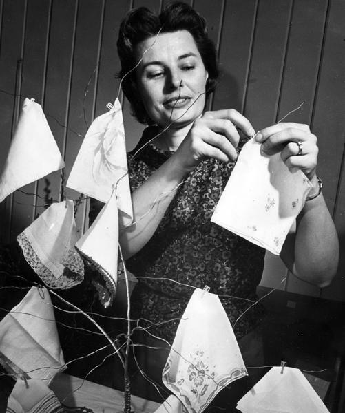 Women replenishes handkerchiefs plucked from her wire tree at bazaar sale.