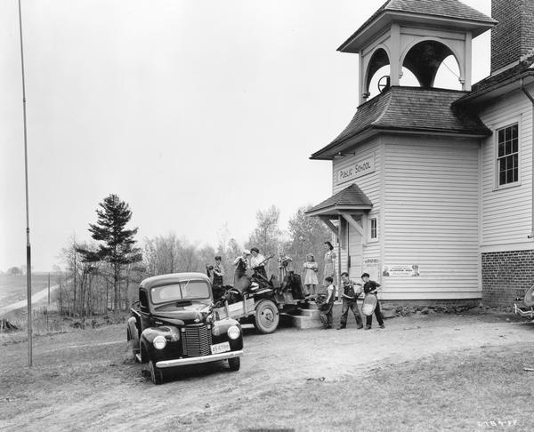 Eight North Bright School pupils and teacher filling International truck and trailer with scrap metal collected for salvage drive during Governor Julius P. Heil's MacArthur Week. The school was three miles from Owen in Clark County. Marie Carpenter of Abbotsford was the teacher and had twenty-three pupils ranging in age from five to twelve years. The children collected enough scrap to fill the truck and a big trailer. Miss Carpenter said they were planning to buy a hot plate and other articles from the proceeds.