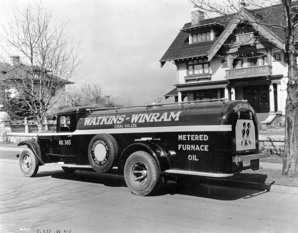 International Model A-4 truck delivering heating oil to residential home in Vancouver, British Columbia, 1933.  Truck was owned by Watkins-Winram Coal Co. Ltd., Vancouver, British Columbia. Racist caricatures of African Americans representing "Coal" and "Oil" are painted on the back of the truck.