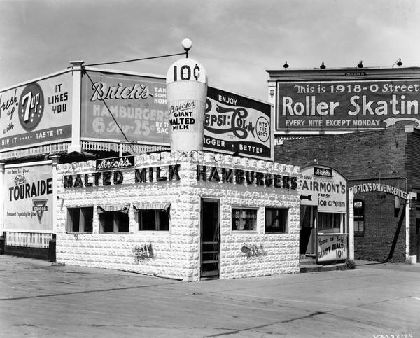 Brick's Hamburger Place owned by Myles B. Willis. Brick's specialized in malted milks, Fairmont ice cream, and drive-in service and used International Harvester refrigeration equipment. Billboards advertising Conoco, 7 Up, Pepsi Cola, and a roller skating rink are also shown.
