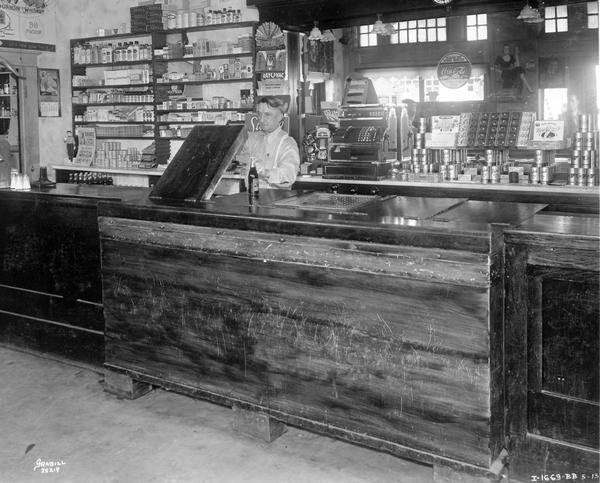 Male bartender at Clyde Cockersham's Bar. The bar was equipped with a McCormick-Deering ten can cooler.