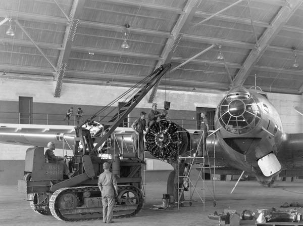 Military mechanics and TD-14 crawler tractor with a Hughes-Keenan Crane servicing a B-17 bomber in MacDill Field hanger. MacDill Field, now MacDill Army Air Base, was activated shortly before the outbreak of World War II. Its first mission was to train airmen on B-17 and B-26 bombers.