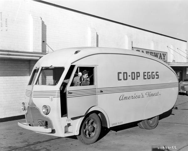 Man driving an egg-shaped "Co-op Eggs" truck outside a Safeway grocery store. The truck is an International D-300 operated by the Washington Cooperative Egg and Poultry Association.