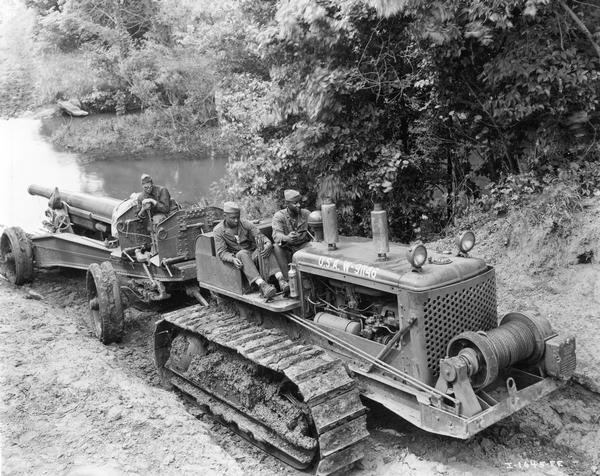 Three African American field artillery soldiers crossing a creek on a TD-18 diesel crawler tractor (TracTracTor) and 155 mm gun. The soldiers were from Battery F of the 349th Field Artillery, Fort Sill, Oklahoma. The commanding officer of the 349th was Colonel A.L.P. Sands.