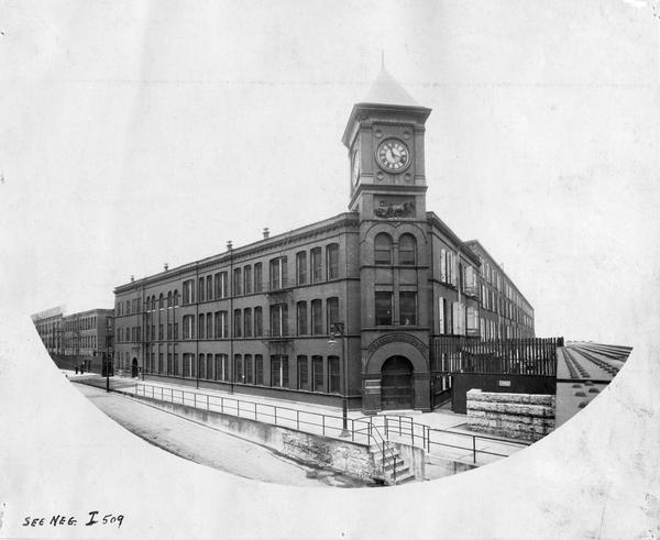 William Deering & Company factory as viewed from across Fullerton Avenue. The factory was built by William Deering in 1880. In 1902 it became International Harvester's Deering Works. The factory was located at Fullerton and Clybourn Avenues and closed in 1933.<br>The wording above the arch reads: "William Deering & Co." There are two smaller signs to the left of the door that read: "International Harvester Company," and "Deering Harvester Company."