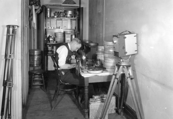 Man working on reels of 35mm film for International Harvester's Agricultural Extension Department.