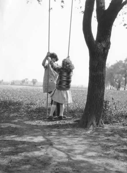 Two young girls playing on a tree swing on the grounds of Viall School.