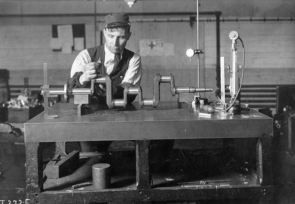 A worker at International Harvester's Akron Works testing a truck engine crankshaft with a micrometer. The factory was owned by the Aultman & Miller Buckeye Company until the company was purchased by International Harvester in 1905. The factory burned in 1907 but was rebuilt in 1912.