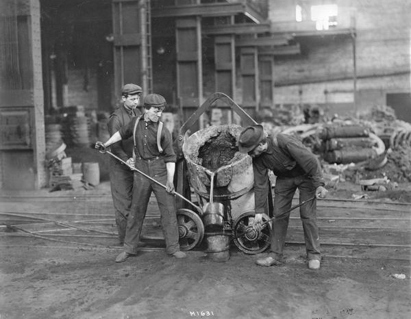 Three workers pouring molten metal into small containers at International Harvester's Milwaukee Works. The factory was owned by the Milwaukee Harvester Company until 1902.