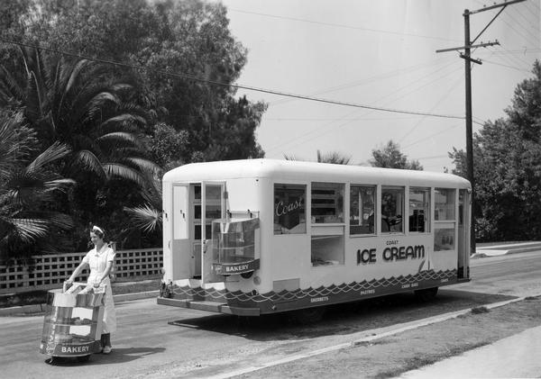 Female employee of the Coast Ice Cream Company delivering baked goods with a special bakery cart taken from the back of a specially modified International C-300 ice cream truck. The truck features an approximate 130 inch wheelbase and 20 foot body.