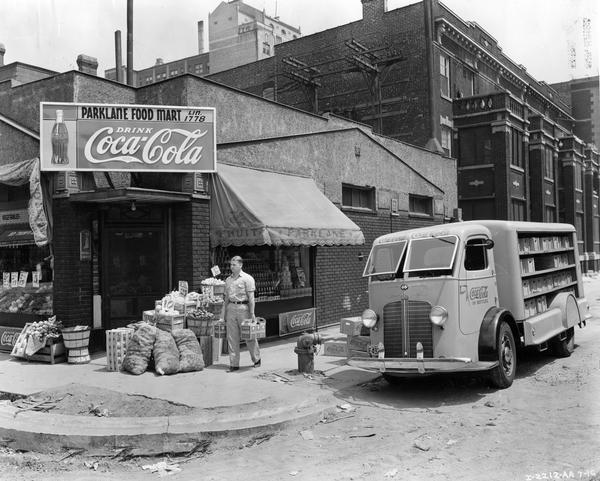 Man delivering bottled Coca-Cola soft drinks (soda) from an International C-300 truck with covered deck body. The delivery was to Parklane Food Mart, which sits on a dilapidated corner of North Clark Street.