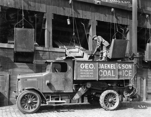 African American workman filling an International Model "63" coal and ice truck.  The truck was owned by George Jaekel & Son Coal and Ice Company based in Newark, New Jersey.