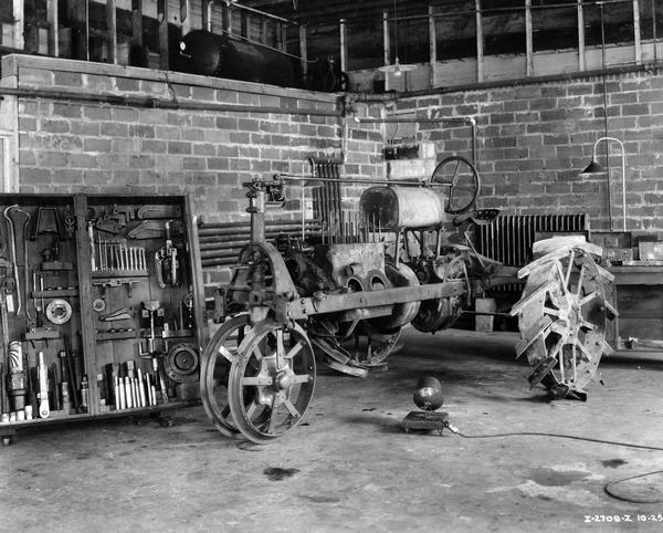 Interior of a service shop in a McCormick-Deering dealership with a disassembled Farmall Regular tractor and a wooden tool rack. The tractor was originally purchased in 1924 and had its engine block replaced in the shop.