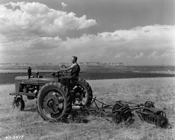 Wayne Pattison working the fields of his two-hundred and eighty acre farm with a Farmall H tractor and a McCormick-Deering No. 7 disc plow. In the background along the horizon is the Scotts Bluff National Monument.