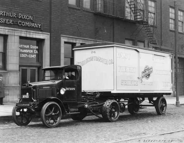 Man driving an International heavy-duty freight service truck owned and operated by Arthur Dixon Transfer Company.