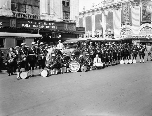 Members of Minneapolis Chapter No. 1 of "World's War Disabled American Veterans" (World War I) posing with musical instruments in a city street in front of an International motor coach or bus. The bus is built on an International model 52 or model 53 chassis.