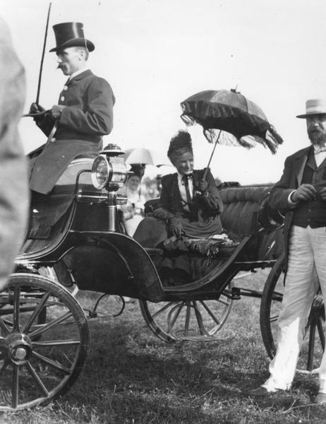 Nettie Fowler McCormick (1835-1923), wife of inventor and industrialist Cyrus Hall McCormick (1809-1884), at the Paris Exposition of 1900. Mrs. McCormick is seated in an open coach with a windblown parasol held over her head. Her son Cyrus McCormick, Jr. is standing to her right. The McCormick Harvesting Company displayed many products and took several prizes at the Paris Exposition. Photograph taken by John F. Boeyer, foreign representative for the McCormick Company.