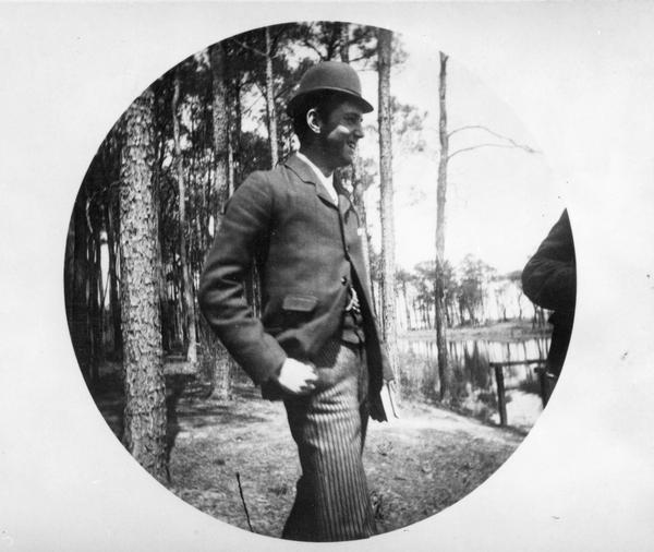 Candid outdoor photograph of a young Stanley Robert McCormick (1874-1947), son of inventor and industrialist Cyrus Hall McCormick (1809-1884). Mr. McCormick is standing in a wooded area near a lake with what appears to be a book in one hand.