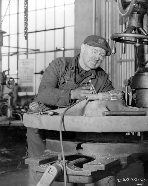Worker at a Hawkins Mine machine shop checking a measurement on a large casting under a trouble light. Hawkins Mine was a subsidiary of International Harvester and was located in Itasca County, Minnesota.