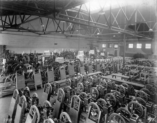 Stationary engines of various sizes stored in neat rows at International Harvester's Tractor Works. Wooden skids are leaning against many of the engines. Included are Mogul, Mogul Jr. and Mogul hopper cooled engines. In operation from 1910-1972, the works was located at 2600 West 31st Boulevard. The works occupied 82 land acres and 33 buildings, and employed 5000 people as of 1960. The works later closed in 1972 when construction equipment manufacture was moved to Melrose Park Works. Products: tractors (including Farmall A and B from 1939-1947), construction equipment, crawler tractors.