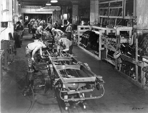 Workers on an assembly line building and adjusting truck chassis's and engines at International Harvester's Chatham Works, Ontario, Canada. The factory was owned by the Chatham Manufacturing Company until 1910. The factory produced wagons and sleighs until 1935. In 1921 the factory began manufacturing trucks.