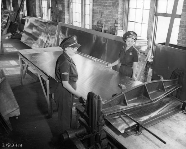 Two female sheet metal workers fabricating engine cowlings for Curtiss-Wright C-46 Commando cargo and transport planes at the International Harvester's Auburn Works. The factory was located at 5 Pulaski Street and was formerly known as the "Osborne Works." It was owned and operated by the D.M. Osborne Company until International Harvester purchased the company in 1903.