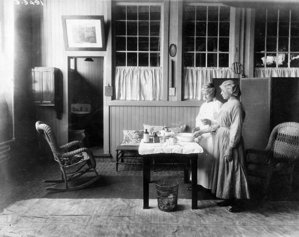 A nurse treating the hand of a female worker in what appears to be a doctor's office or nurse's station at International Harvester's Osborne Twine Mill. The Osborne Works was located at 5 Pulaski Street. It was owned and operated by D.M. Osborne and Company until the company was purchased by International Harvester in 1903. The factory closed in 1951.