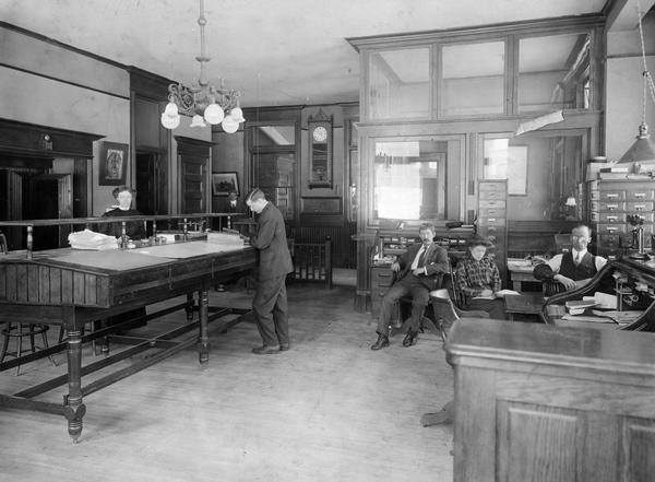 Male and female office workers inside International Harvester's Osborne Twine Mill. The Osborne Works was located at 5 Pulaski Street, and was owned and operated by D.M. Osborne and Company until the company was purchased by International Harvester in 1903. The factory closed in 1951. Products: balers, cultivators, harrows, broadcast seeders, hay tedders, hay presses, stalk cutters, potato machines, weeder-mulchers, binder twine (until 1925).