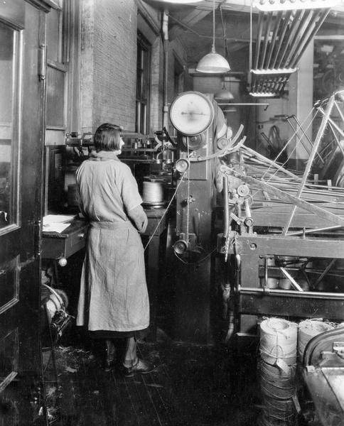 Female employee balling twine with a large twine baller at International Harvester's McCormick Twine Mill. The McCormick Works was in operation from 1873-1961 and was located at Blue Island Avenue and Western Avenue in the Chicago subdivision called "Canalport."