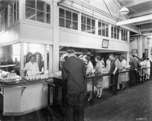 Male and female workers lined up at a food service window in the cafeteria of International Harvester's Hamilton Twine Mills, Hamilton, Ontario, Canada.