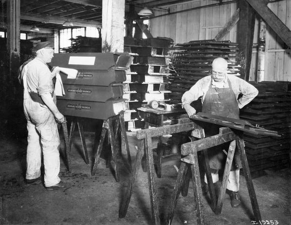 Two workers, one applying decals and the other adding pinstriping to wagon boxes at International Harvester's Weber Wagon Works in Auburn Park. The factory was owned by the Weber Wagon Company until 1904, when it was purchased by International Harvester.