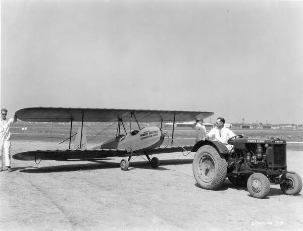 Three crewmen are using a McCormick-Deering I-12 industrial tractor to pull a glider during the American Air Races held at Chicago's Municipal Airport, July 1-5. The glider pictured held the world's record for most consecutive loops.