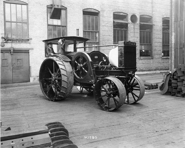 Man operating a new International Titan 30-60 H.P. tractor outside an International Harvester factory.