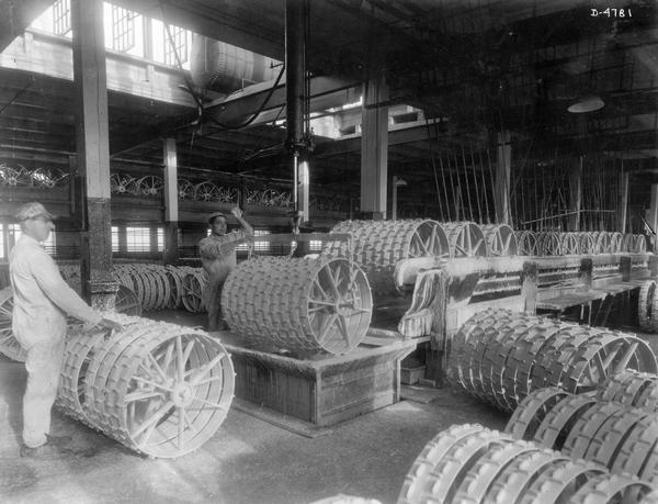 Two workers dipping mower wheels in paint at International Harvester's Deering Works. The factory was owned by the Deering Harvester Company before 1902. It was located at Fullerton and Clybourn Avenues.