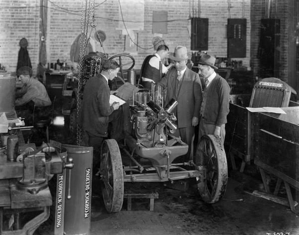 Factory Superintendent E.C. Lutz (center) and Assistant Chief Inspector F.H. Pfhol (right) look over a McCormick-Deering 10-20 tractor torn down for inspection under the supervision of R. Blair (left), special tear-down inspector at International Harvester's Tractor Works.
