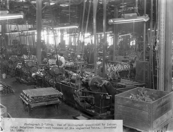 Workers operating machines at International Harvester's Tractor Works. The original caption reads: "Use of photograph questioned by Industrial Relations Department because of the unguarded belts; November 15, 1930."