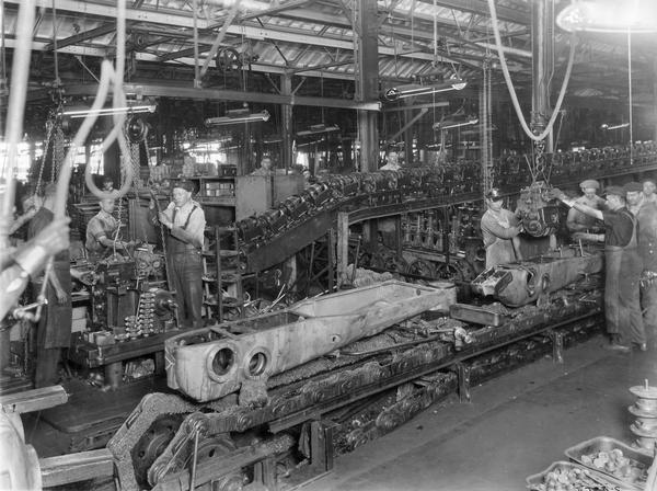 Workers installing the transmission in a crawler tractor chassis along an assembly line at International Harvester's Tractor Works.