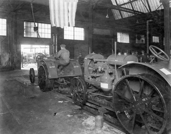 Worker riding a McCormick-Deering 10-20 HP tractor off an assembly line at International Harvester's Tractor Works.