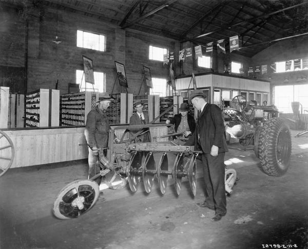 International Harvester dealer showing a trailing five bottom disk plow hitched to a Farmall tractor to customers.